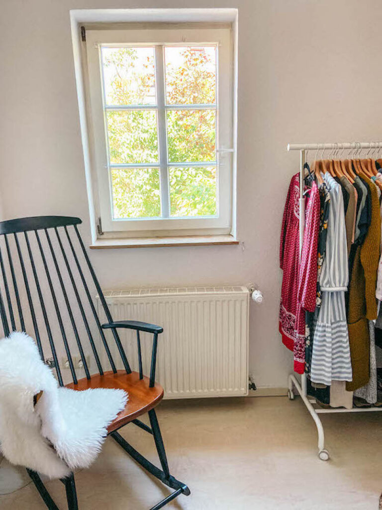 Picture of a rocking chair and a clothing rack in a bedroom