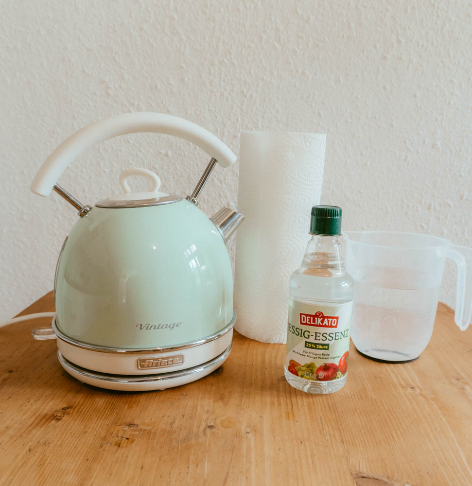 Kettle, paper towel, vinegar, and water on a kitchen table