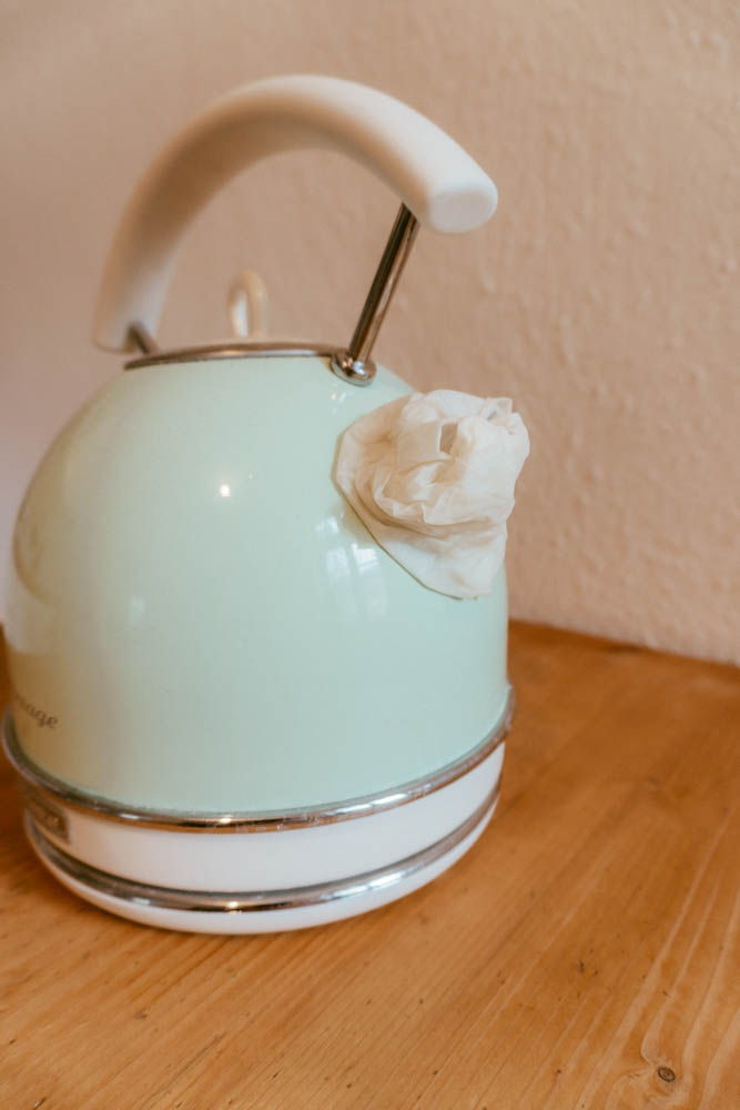 a kettle with paper towel dipped in vinegar wrapped around its spout to clean it. 