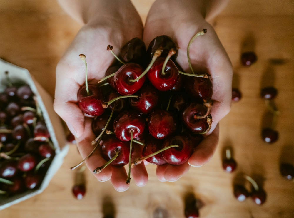 someone holding a handful of cherries in her hand