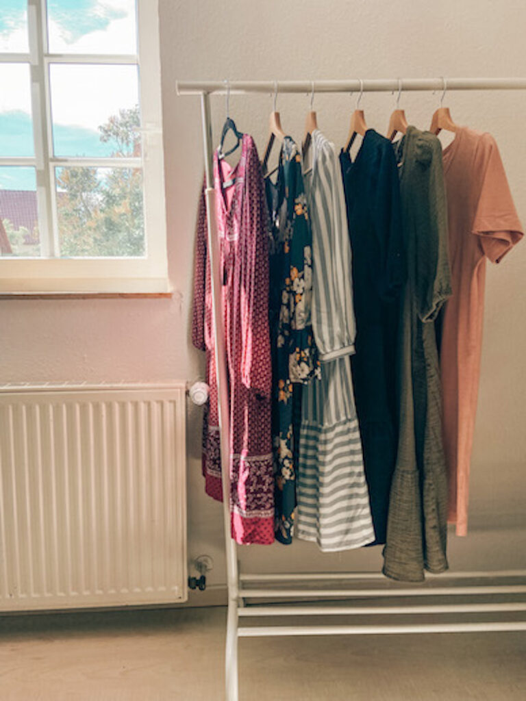 six dresses hanging on a clothing rack.