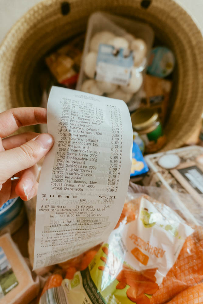 Someone holding a grocery receipt in front of the groceries